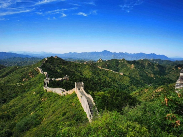 pexels-photo-14533501-14533501 Stunning aerial view of the Great Wall of China winding over lush green hills under a clear blue sky.