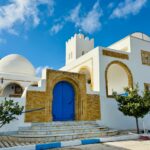 Captivating view of a Tunisian building with iconic blue door under a clear sky.